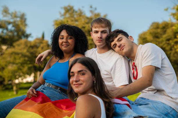 Friends sitting together in a park, expressing their support for lgbtq+ rights with a rainbow flag